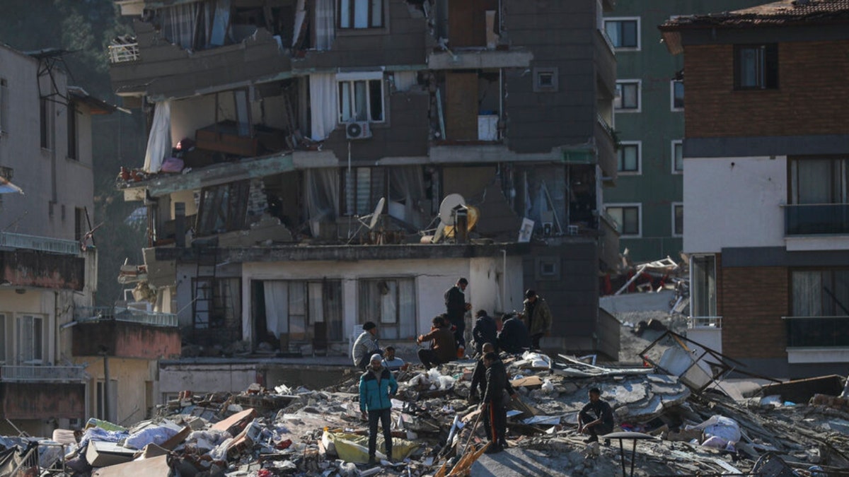 Men walk among the debris in Hatay, Turkey