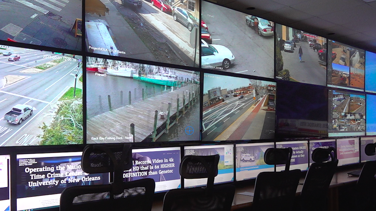 Large tv monitors showing numerous security camera feeds, mostly busy roads and neighborhoods