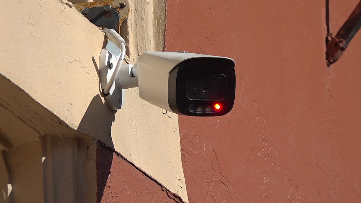 Security camera blinking hanging on the outside wall of a building