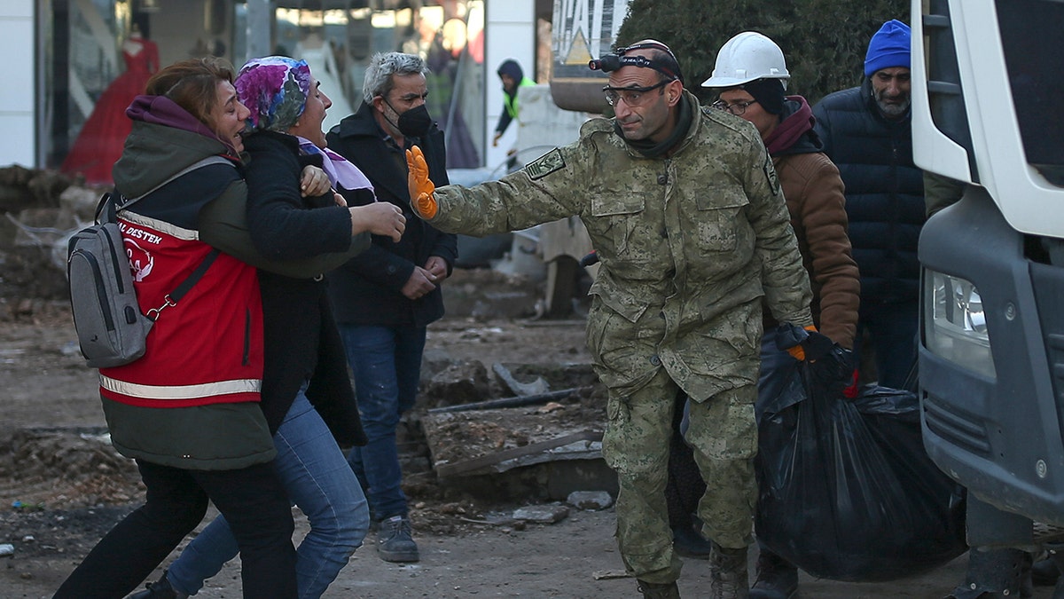 Turkey Syria earthquake victim's body is carried by workers as woman cries out in anguish