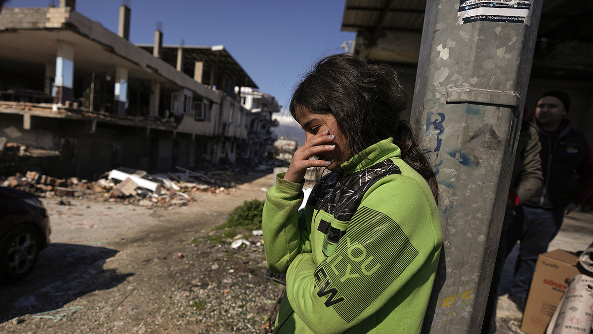 Girl stands next to destroyed buildings in Turkey