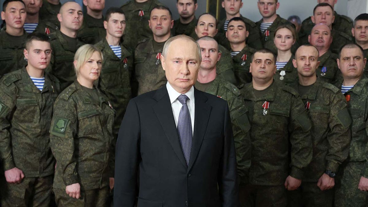 Vladimir Putin stands in front of a group of soldiers.