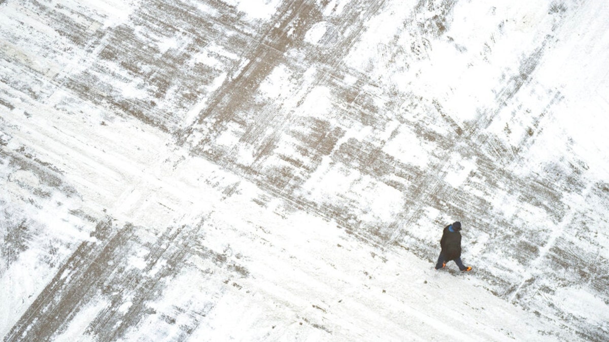 A man walks across snowy Minneapolis streets