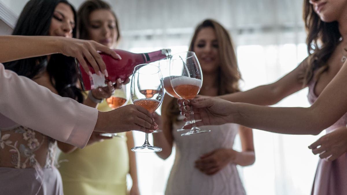 Bride drinking with bridesmaids and guests