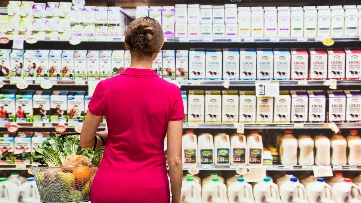 Woman looks at milk shelves in grocery store