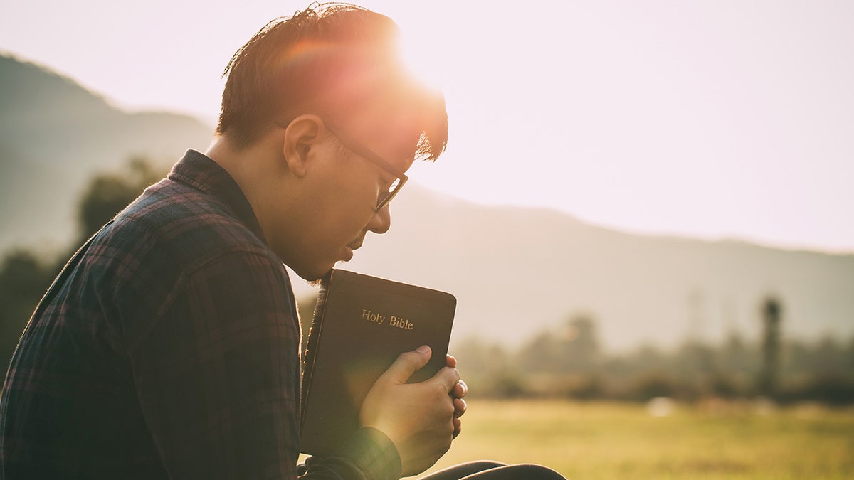 homem orando enquanto segura a Bíblia