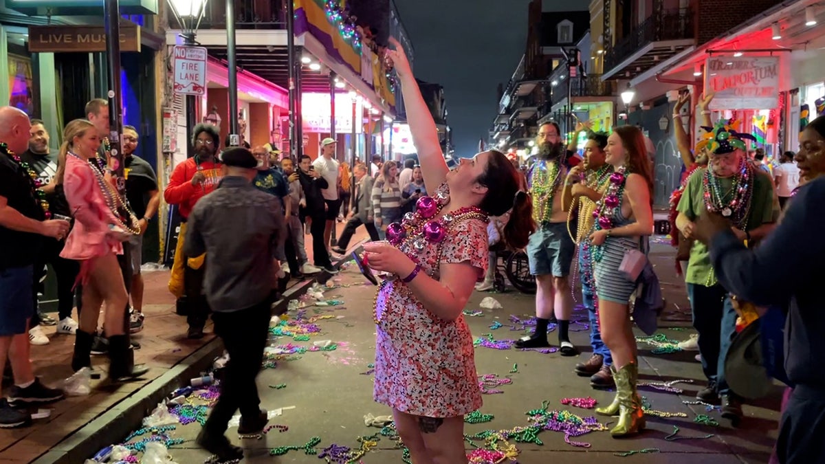 Frau im Kleid greift nach Perlen während des Karnevals in New Orleans