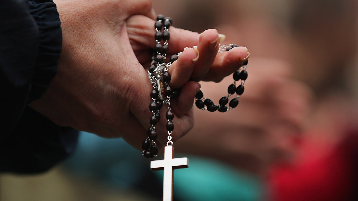 woman holds rosary beads