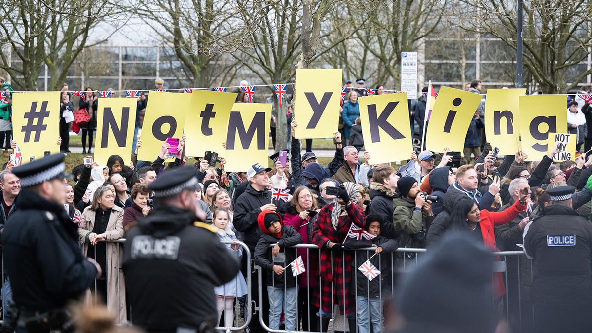 protesters hold up signs that say 'not my king'