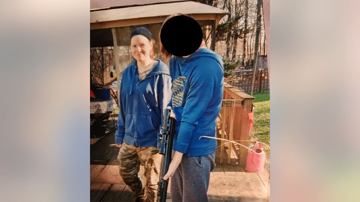 Sarah Beth Clendaniel seen next to another individual with a rifle