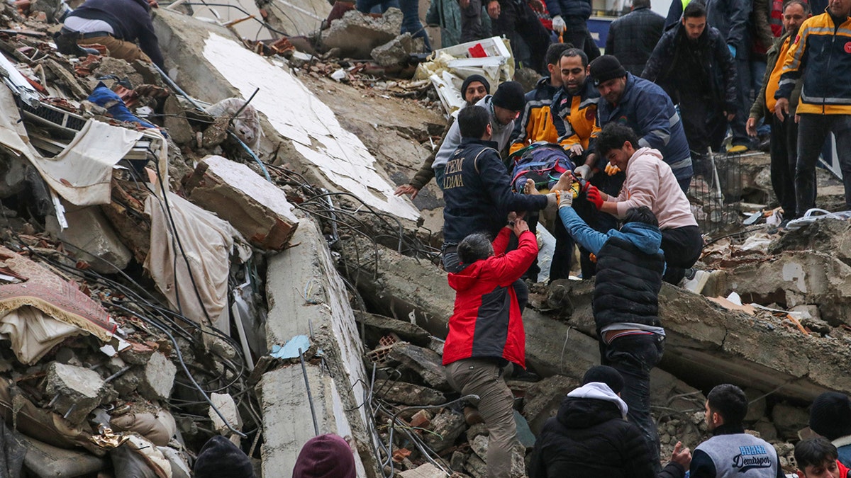 people helping injured man on rubble