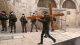 A Christian man carries a cross
