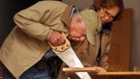 Jimmy Carter saws a piece of wood.