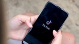 A girl holds a phone with TikTok open