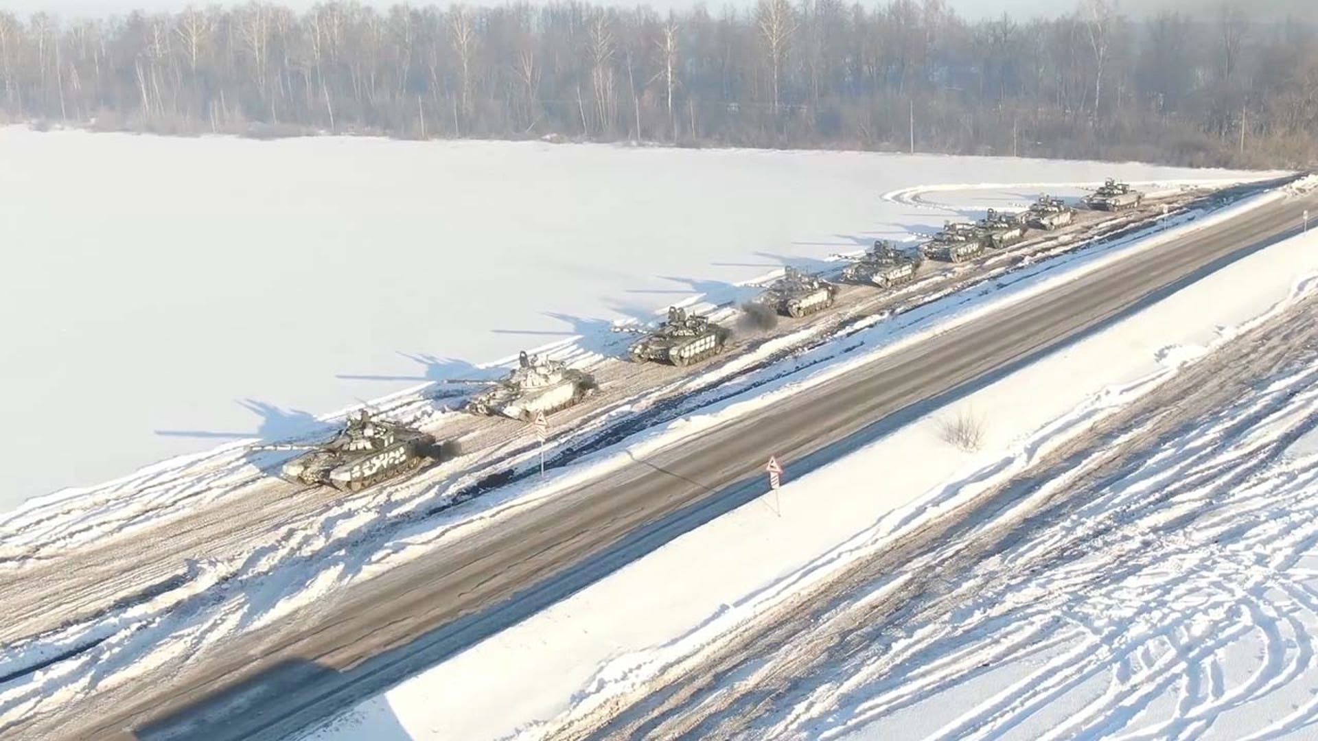 A line of military tanks along a snow covered street.