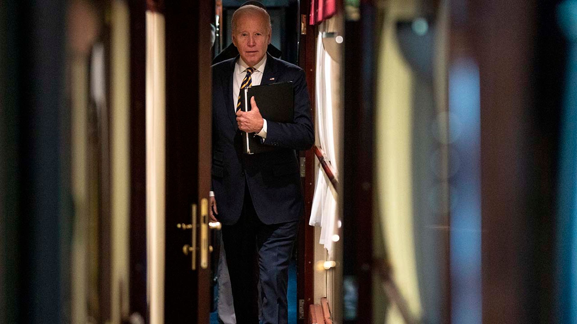 President Joe Biden walks down a train hallway.