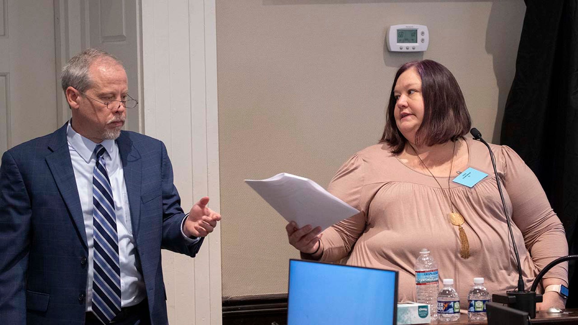 A woman and man examine paperwork while in a courtroom.