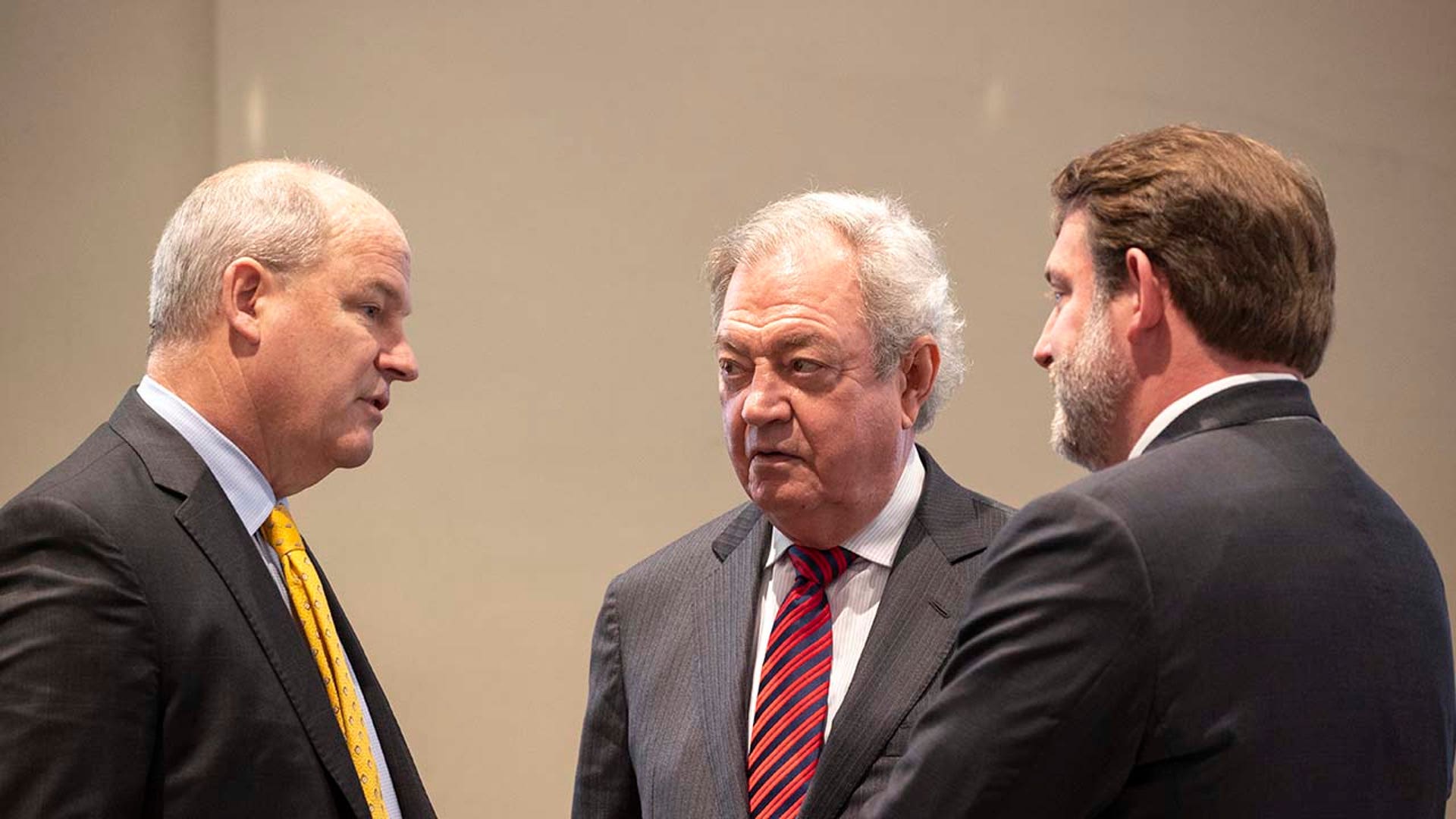 Three men speak inside a courtroom.