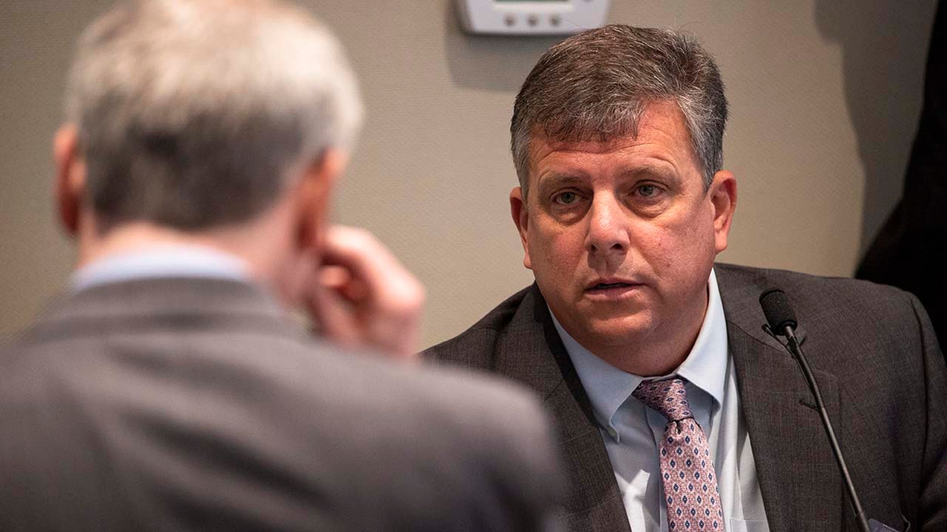 A man testifies on the witness stand in a trial.