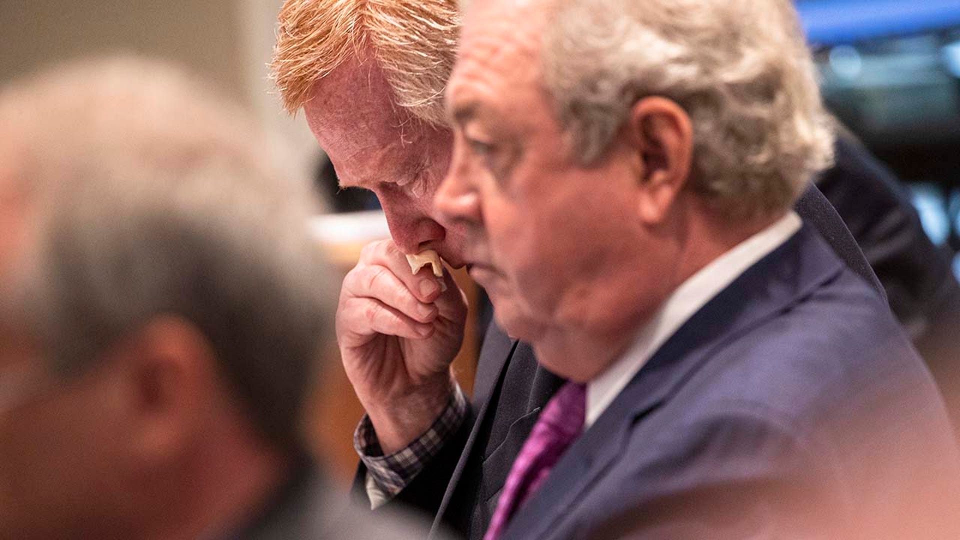 A man wipes away a tear inside a courtroom.