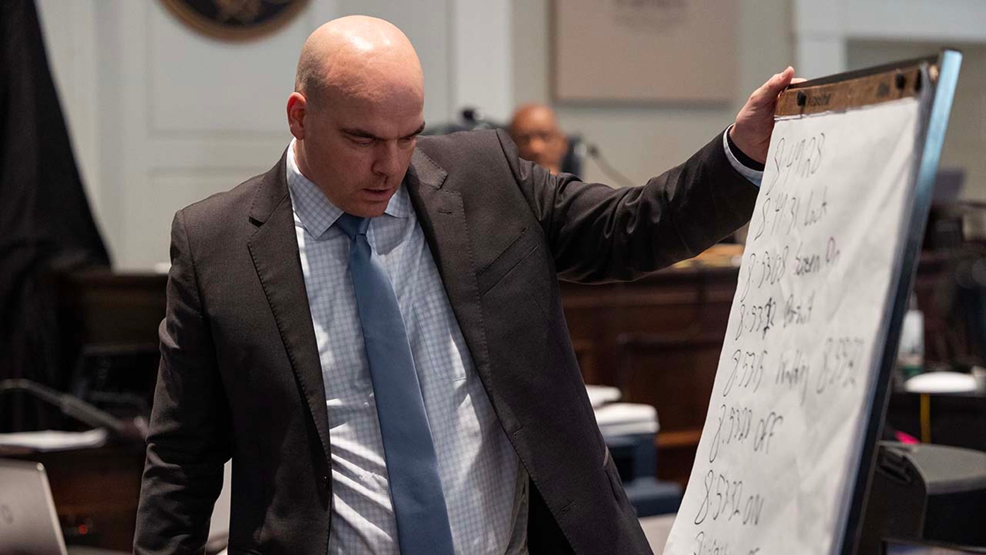 A man looks at a poster inside a courtroom.