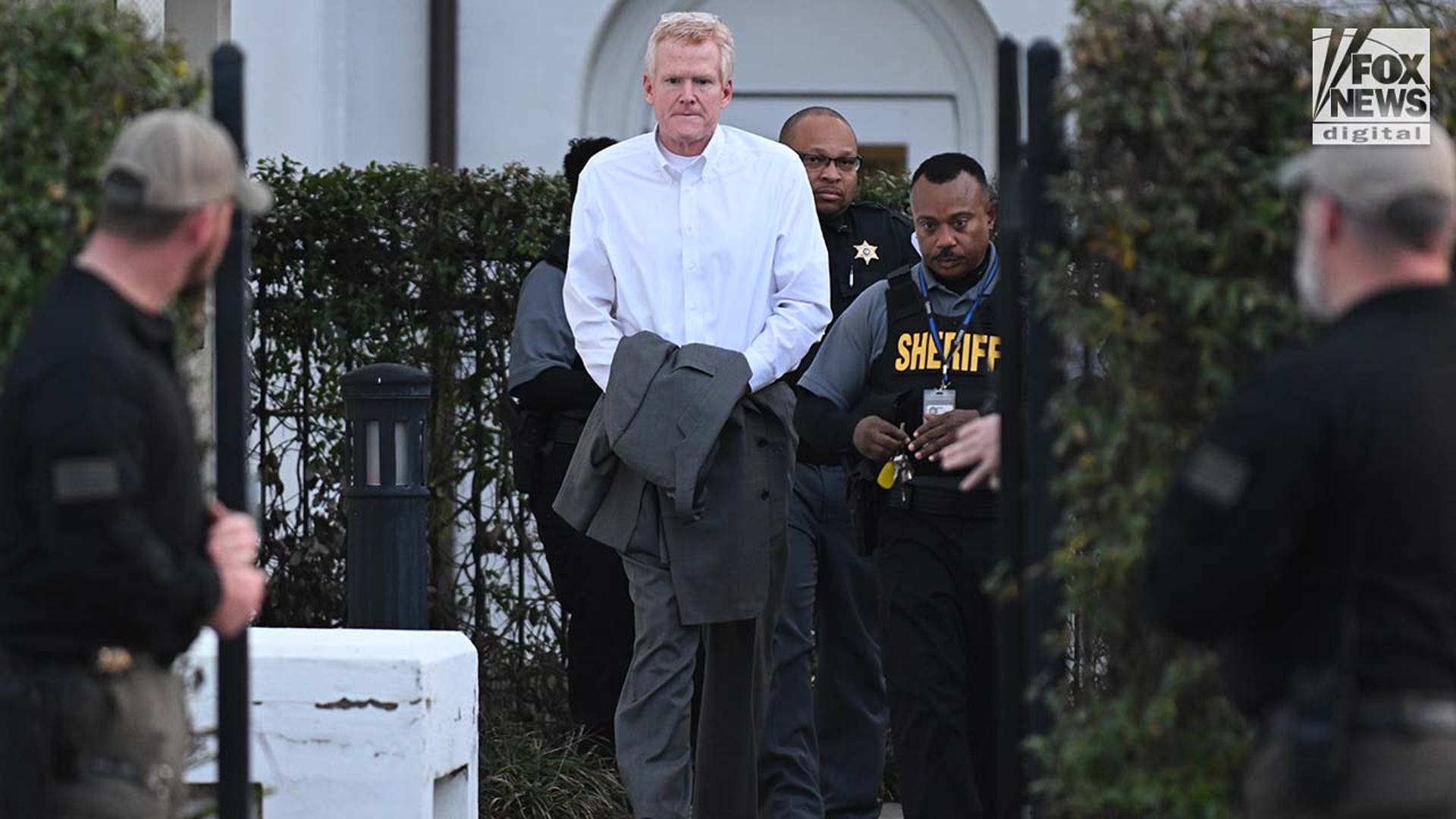 A man is escorted out of a courthouse in handcuffs, by police.