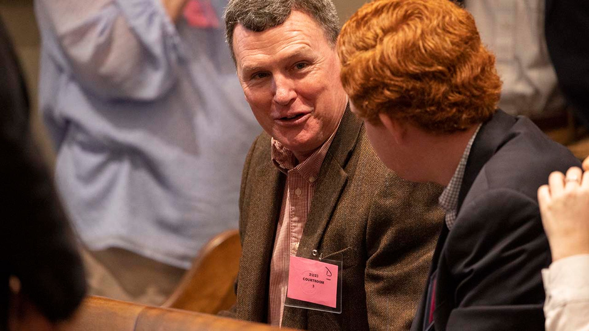 Two men speak while seated inside a courtroom.