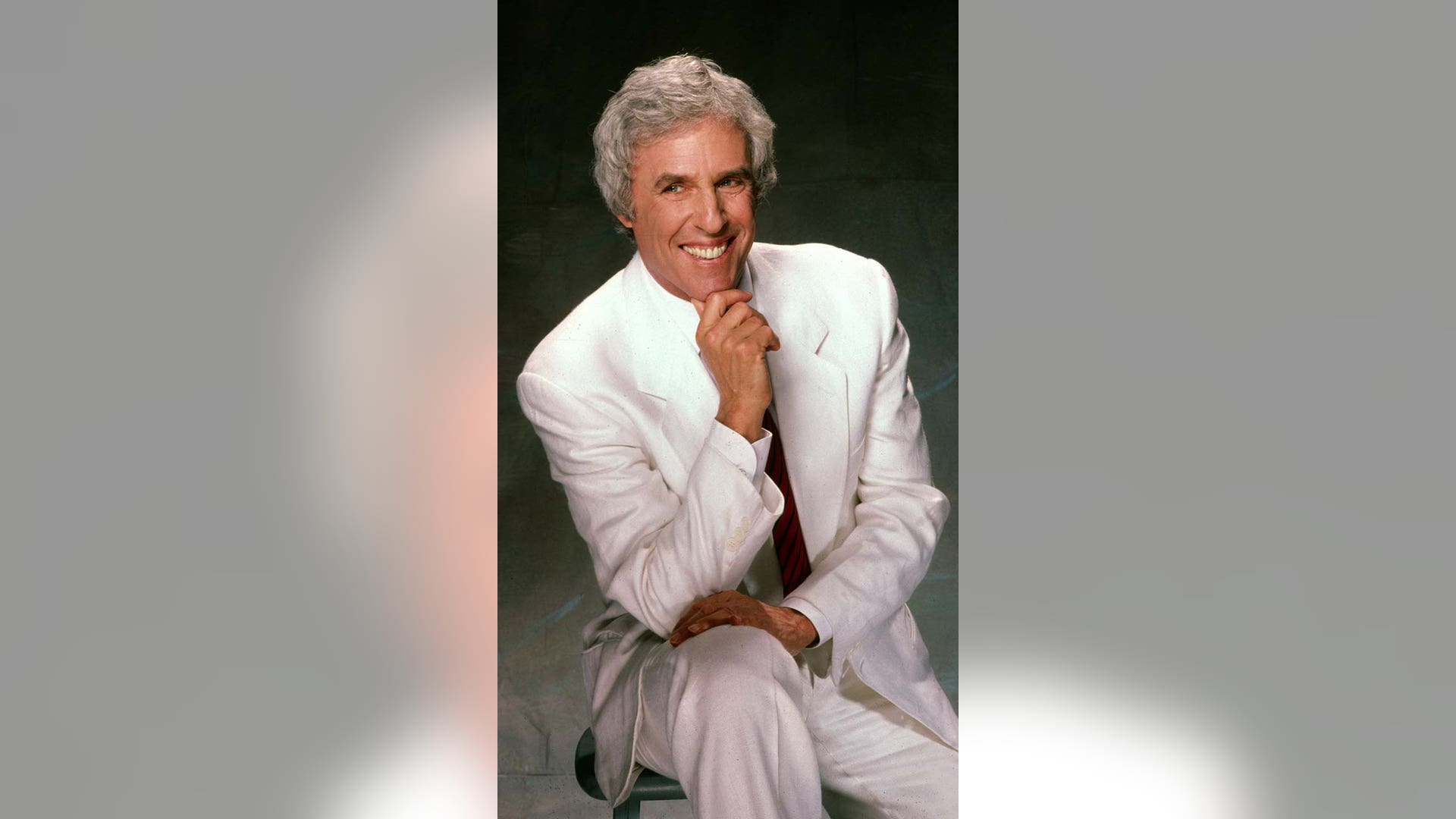 Burt Bacharach posing for a picture with a green backdrop