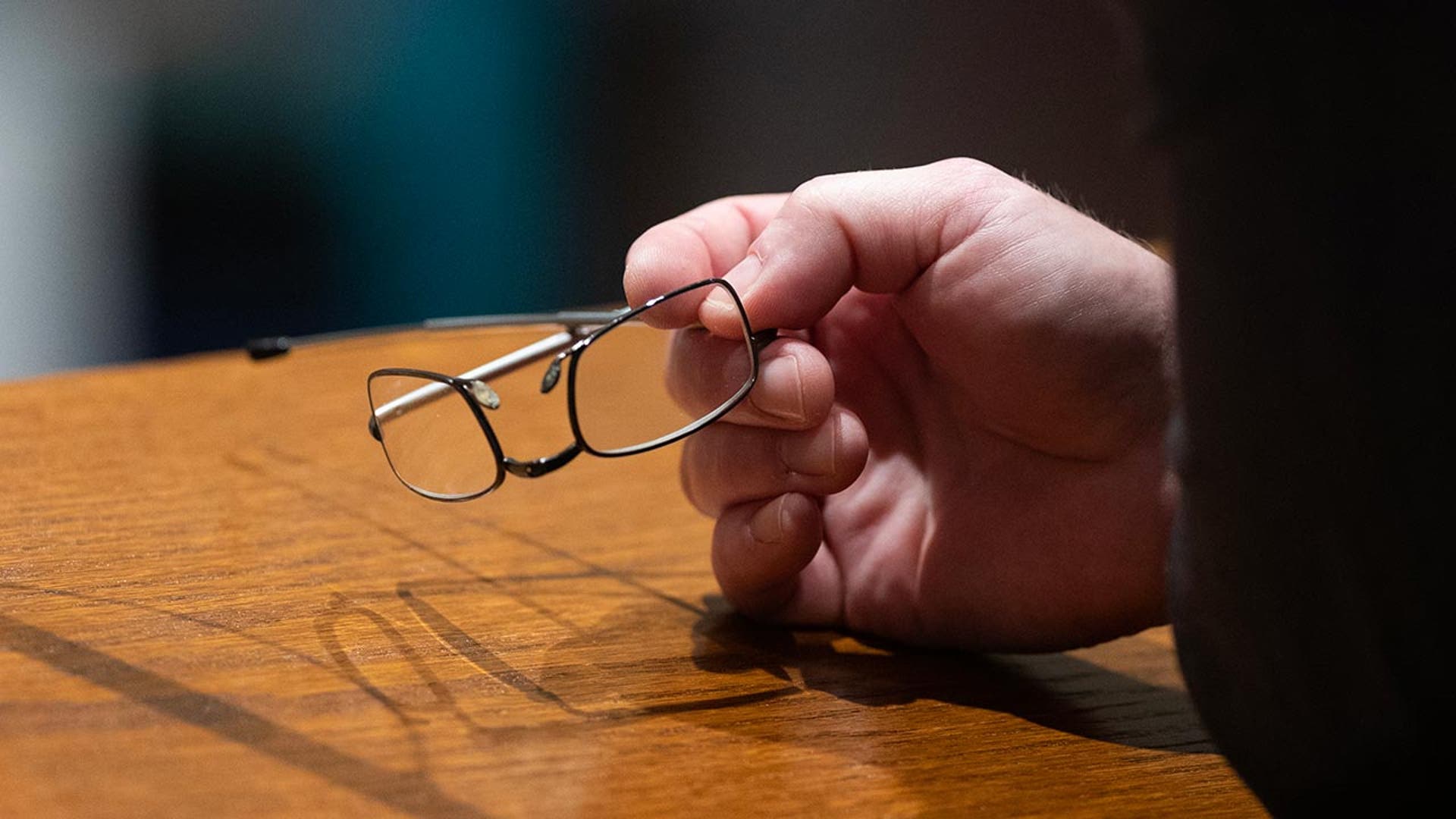Close up of a hand on a desk holding glasses