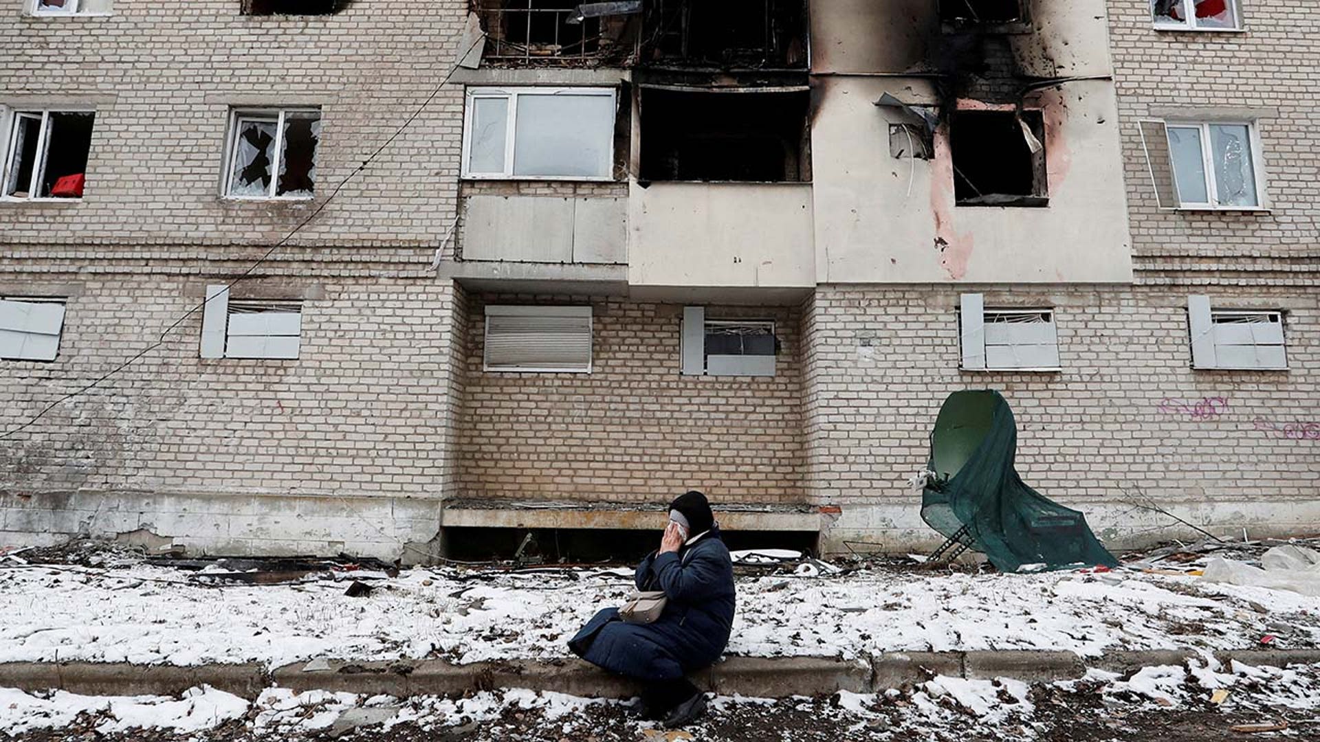 A woman weeps outside of a destroyed apartment complex.