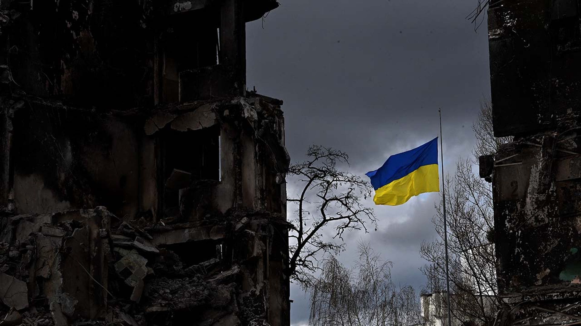 The Ukrainian flag flies among destruction.