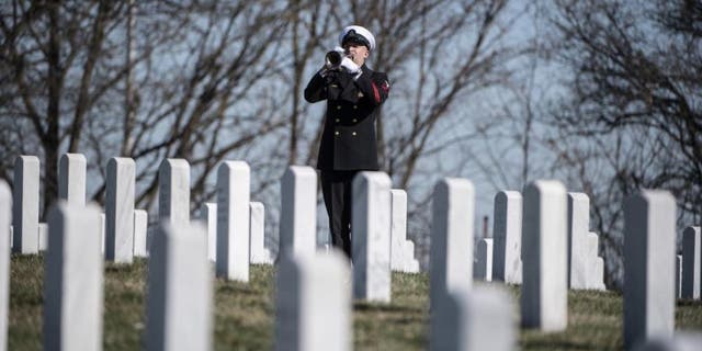 A trumpeter from the U.S. Navy Ceremonial Band plays "Taps" during military funeral honors for U.S. Navy Gunner’s Mate 3rd Class Herman Schmidt in Section 70 of Arlington National Cemetery in Arlington, Va., Feb. 23, 2023. 