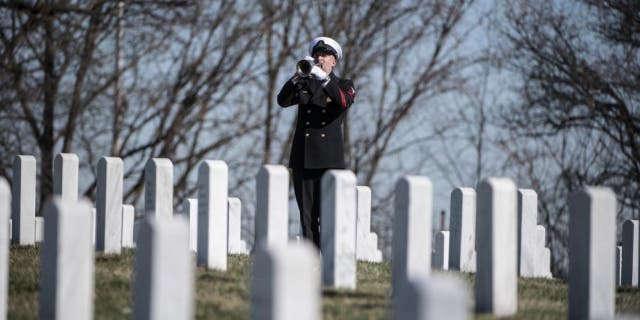 A trumpeter from the U.S. Navy Ceremonial Band plays "Taps" during military funeral honors for U.S. Navy Gunner’s Mate 3rd Class Herman Schmidt in Section 70 of Arlington National Cemetery in Arlington, Va., Feb. 23, 2023. 