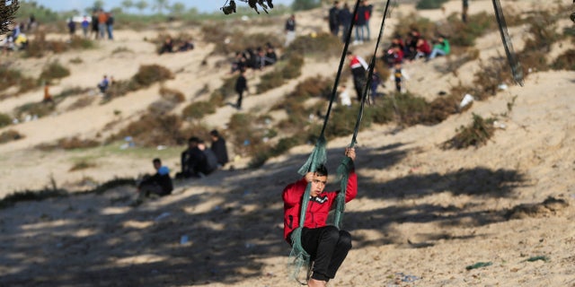 A Palestinian boy sits on a swing hanging from a tree trunk in Rafah city in southern Gaza Strip, February 3, 2023. (Reuters/Ibraheem Abu Mustafa)