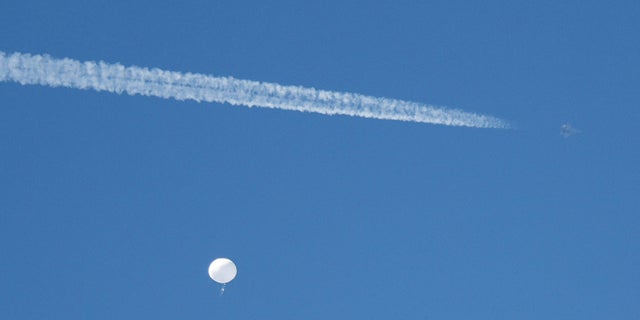 FILE PHOTO: A jet flies by a suspected Chinese spy balloon as it floats off the coast in Surfside Beach, South Carolina, U.S. February 4, 2023.