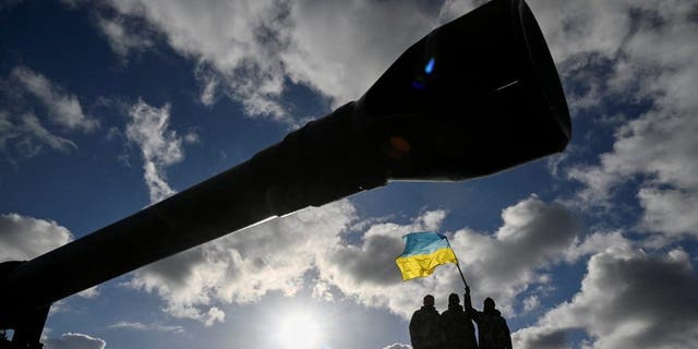 El personal ucraniano lleva la bandera ucraniana mientras se paran en un tanque Challenger 2 durante el entrenamiento en Camp Bovington, en el suroeste de Gran Bretaña, el 22 de febrero de 2023.