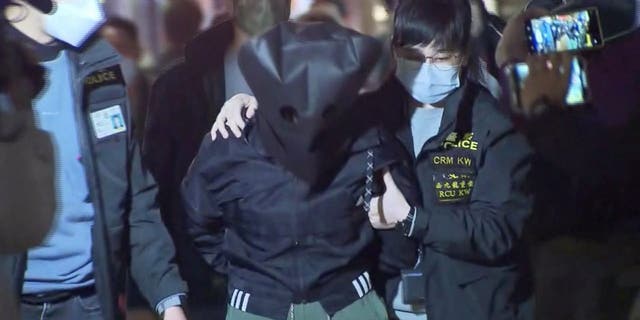 Los agentes de policía escoltan a un sospechoso de 47 años en relación con el asesinato de la modelo Abby Choi, de 28 años, en Hong Kong el 26 de febrero de 2023 en esta captura de pantalla tomada de un video. 