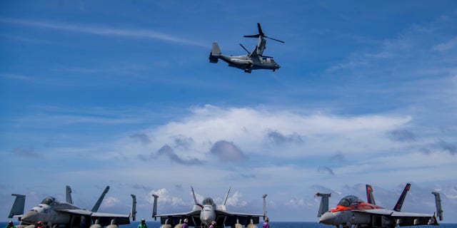 An Osprey flies past the flight deck of the USS Nimitz as it conducts exercises in the South China Sea on Feb. 11.