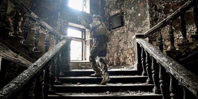 A Russian soldier climbs stairs at the Mariupol drama theatre, hit on March 16 by an airstrike, on April 12, 2022, in Mariupol, as Russian troops intensify a campaign to take the strategic port city, part of an anticipated massive onslaught across eastern Ukraine, while Russia's President makes a defiant case for the war on Russia's neighbor. 