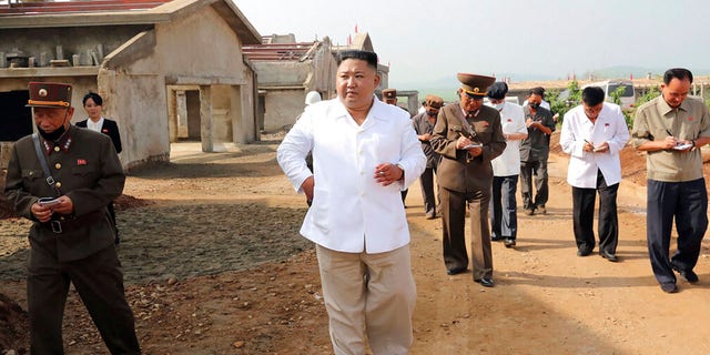 In this undated photo provided on July 23, 2020 by the North Korean government, North Korean leader Kim Jong Un, center, visits a new chicken farm being built in Hwangju County, North Korea.