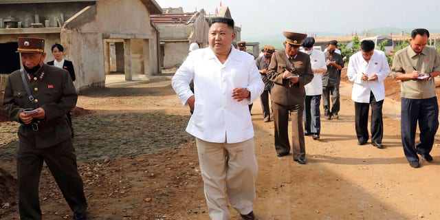 In this undated photo provided on July 23, 2020, by the North Korean government, North Korean leader Kim Jong Un, center, visits a new chicken farm being built in Hwangju County, North Korea.