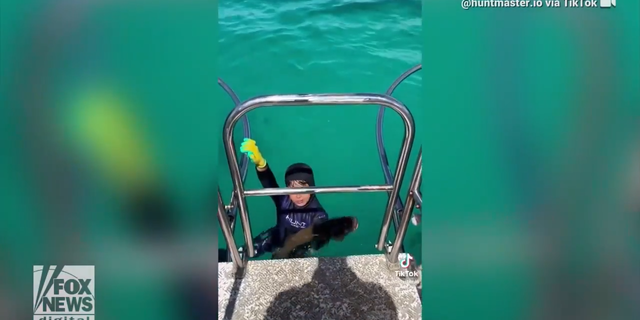 Manni Alam, 8, holds onto the side of a boat in Australia, as seen in a TikTok video gone-viral.