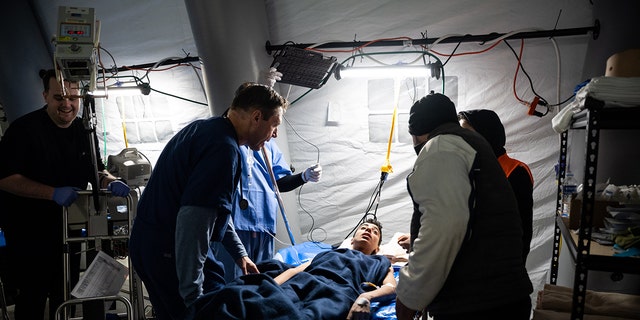 Para dokter dan perawat Samaritan's Purse — di Rumah Sakit Lapangan Darurat Samaritan's Purse yang baru dibangun di Antakya, Turki — berbicara kepada seorang pasien yang terluka akibat gempa bumi baru-baru ini.  