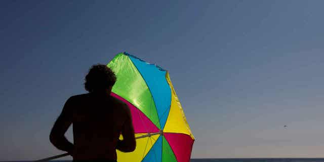 A man folds his umbrella on the beach on Aug. 7, 2018, in Laguna Beach, California. The city council of Laguna Beach is considering a balloon ban.