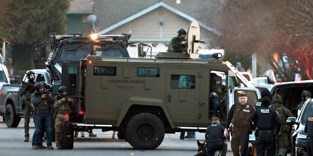 Law enforcement officers aim their weapons at a home during a standoff in Grants Pass, Ore., on Tuesday, Jan. 31, 2023. 