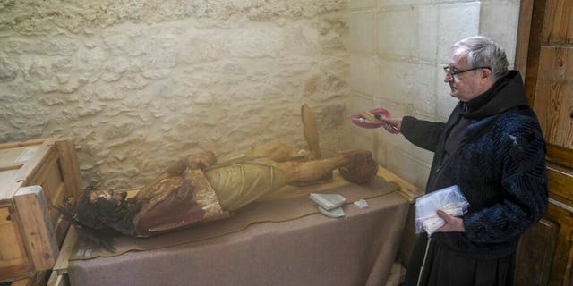 A priest stands by a damaged statue of Jesus in the Church of the Flagellation in Jerusalem's Old City, Thursday, Feb. 2, 2023.