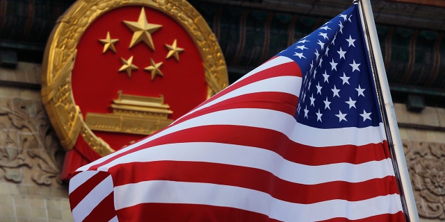 An American flag is flown next to the Chinese national emblem during a welcome ceremony at the Great Hall of the People in Beijing Nov. 9, 2017. 