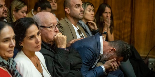 Lucas Delfino, leaning over at right, sits with other members of telenovela star Pablo Lyle's family as he begins to cry as Lyle's sentence is read by Judge Marisa Tinkler Mendez in Miami-Dade Criminal Court in Miami, Friday, Feb. 3, 2023.