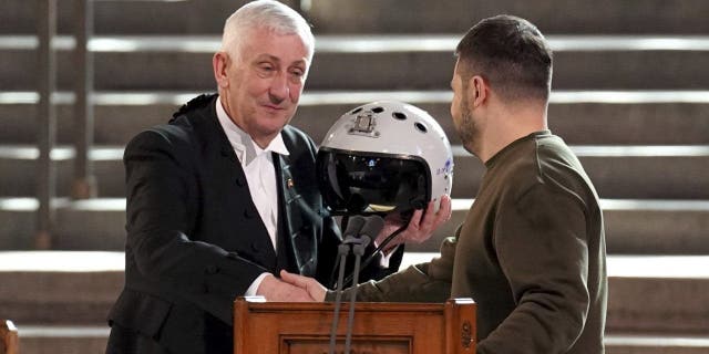 Sir Lindsay Hoyle holds the helmet inscribed with the words 