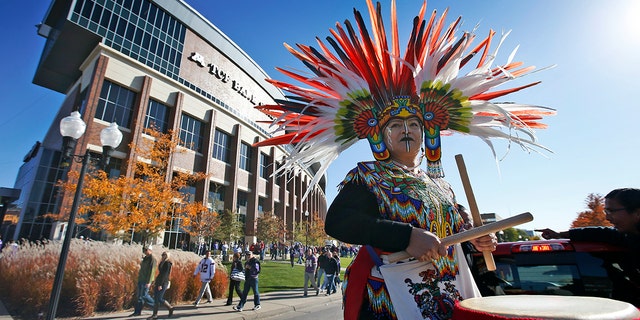 A woman plays a drum during a "No Honor in Racism Rally" in front of TCF Bank Stadium before an NFL football game between the Minnesota Vikings and the Kansas City Chiefs, on Oct. 18, 2015, in Minneapolis. 